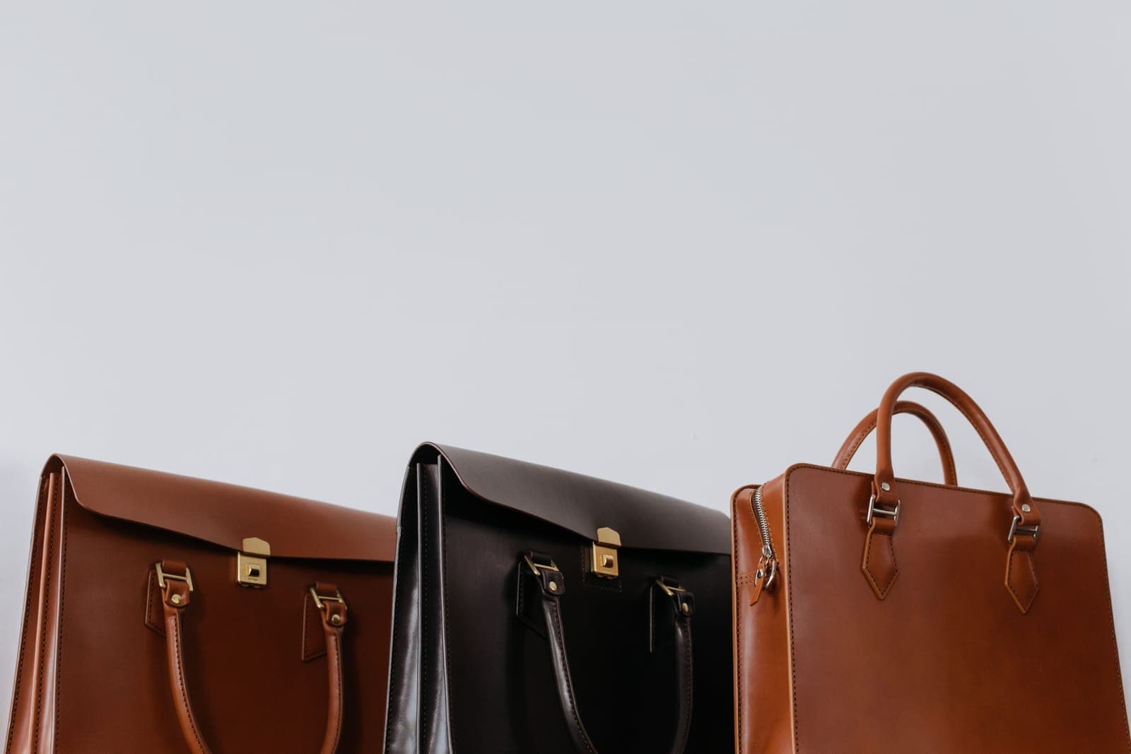 Brown and black leather bags arranged together in warm natural light
